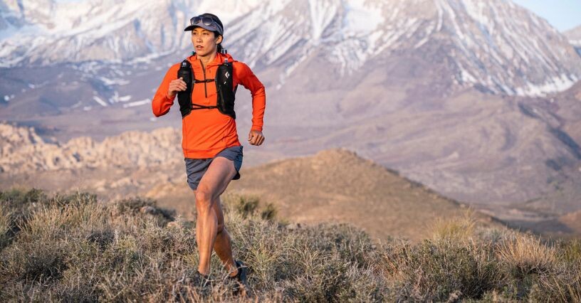Persona corre su un sentiero di montagna con un kit da running