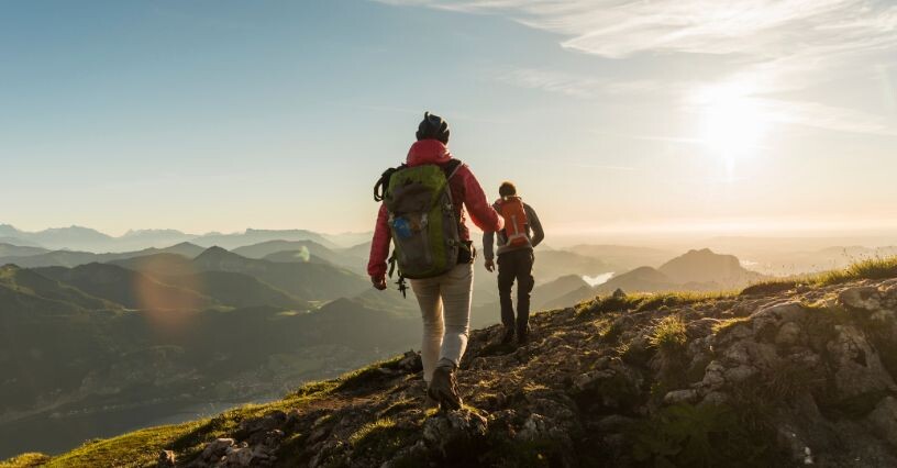 Due persone camminano su un sentiero montano al tramonto