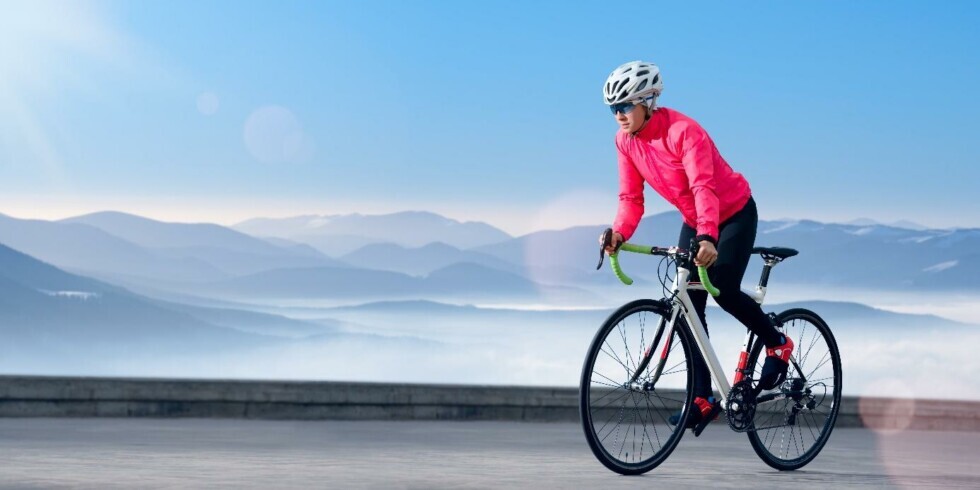 Ciclista pedala su una strada con lo sfondo di montagne