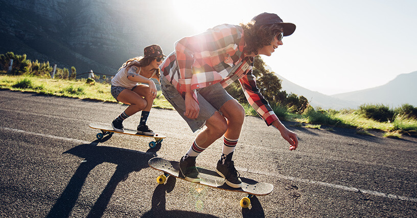 Due persone si divertono a fare longboard su strada