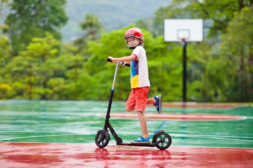 Bambino su monopattino in un campo sportivo