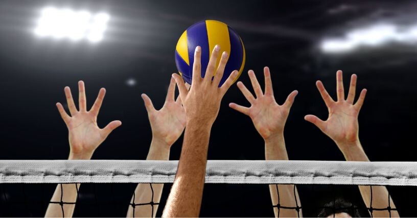 Giocatori di pallavolo saltano per bloccare la palla sopra la rete